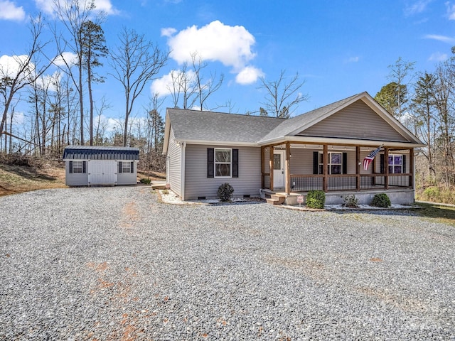 view of front of home featuring gravel driveway, an outbuilding, crawl space, covered porch, and a shingled roof