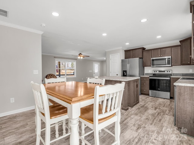 dining space featuring baseboards, light wood-type flooring, crown molding, and ceiling fan
