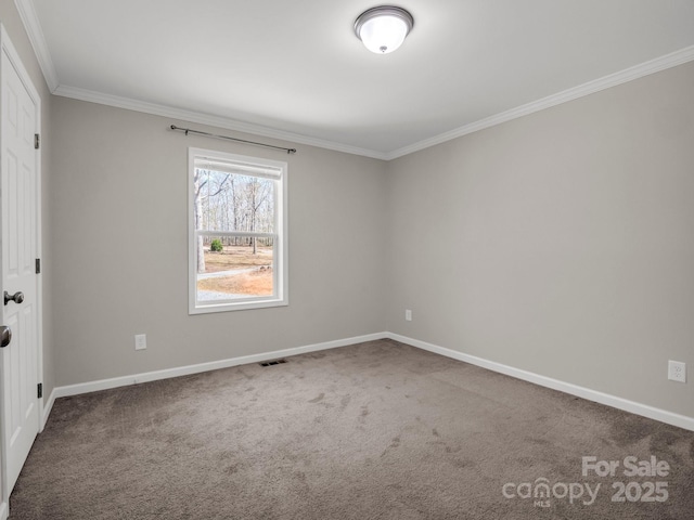 empty room with baseboards, ornamental molding, visible vents, and carpet