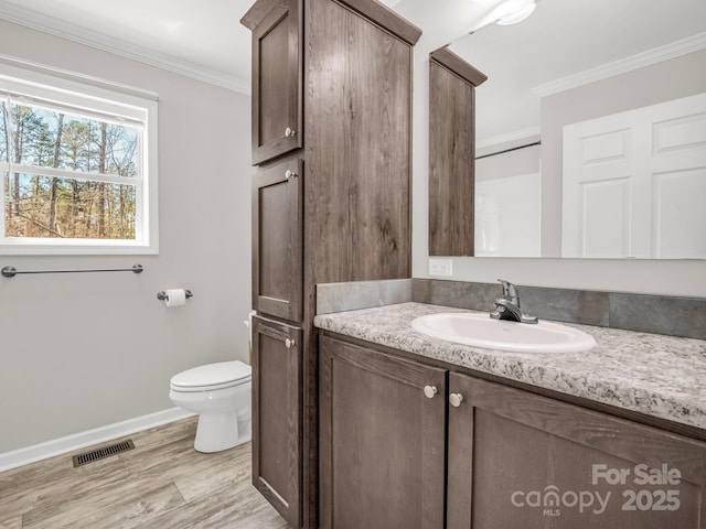 bathroom featuring crown molding, toilet, vanity, wood finished floors, and visible vents