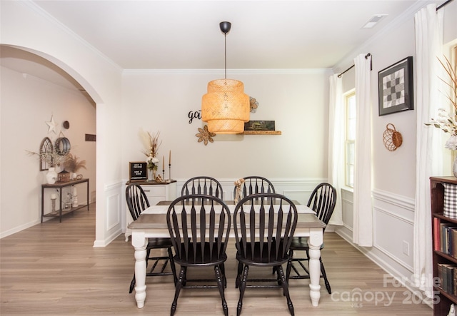 154 Rooster Tail Ln, Troutman, NC 28166 - dining room with light wood-style floors, arched walkways, ornamental molding, and a wainscoted wall