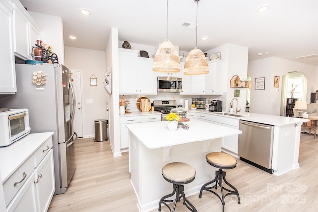 154 Rooster Tail Ln, Troutman, NC 28166 - kitchen with stainless steel appliances, a sink, a peninsula, light wood-style flooring, and light countertops