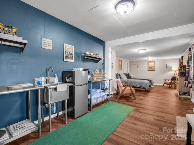 bedroom with baseboards, wood finished floors, and freestanding refrigerator