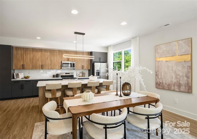 dining room featuring recessed lighting, baseboards, visible vents, and wood finished floors