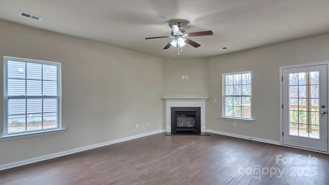 unfurnished living room with a fireplace with flush hearth, baseboards, visible vents, ceiling fan, and dark wood-style flooring