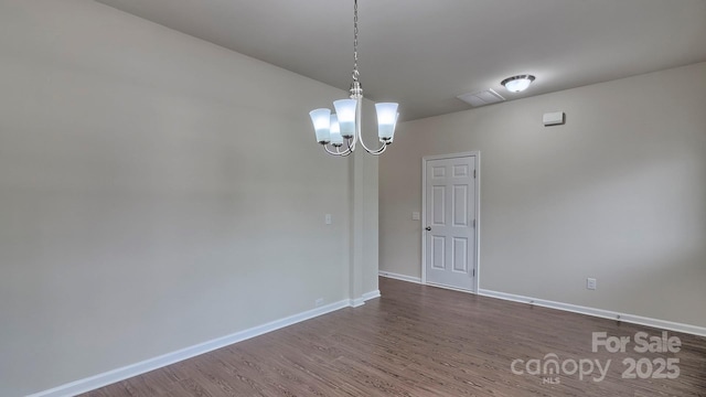 empty room with baseboards, dark wood-style floors, visible vents, and a chandelier
