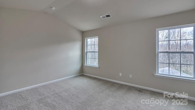 carpeted empty room featuring baseboards, visible vents, and lofted ceiling