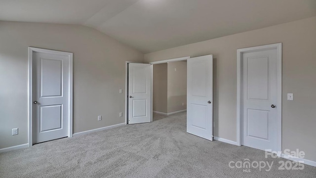 unfurnished bedroom featuring carpet, lofted ceiling, and baseboards