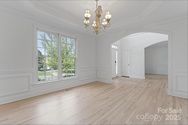 15009 Lisha Ln, Charlotte, NC 28277 - spare room with light wood-type flooring, arched walkways, a decorative wall, and a raised ceiling