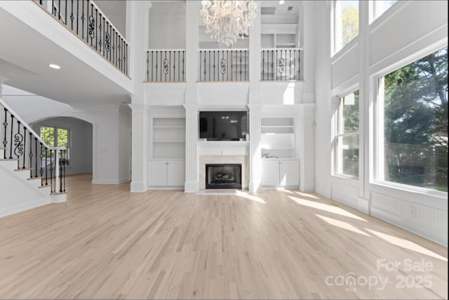 15009 Lisha Ln, Charlotte, NC 28277 - unfurnished living room with built in shelves, wood finished floors, stairway, arched walkways, and a high ceiling