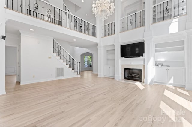 15009 Lisha Ln, Charlotte, NC 28277 - unfurnished living room featuring visible vents, wood finished floors, stairway, built in features, and a glass covered fireplace