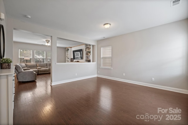 unfurnished living room featuring dark wood finished floors, baseboards, and visible vents
