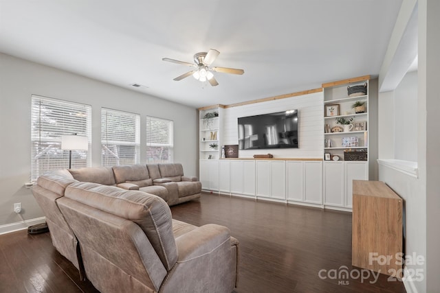 living area featuring baseboards, ceiling fan, and dark wood-style flooring