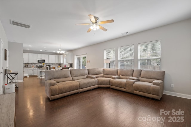 living room featuring recessed lighting, dark wood-style flooring, ceiling fan with notable chandelier, baseboards, and visible vents