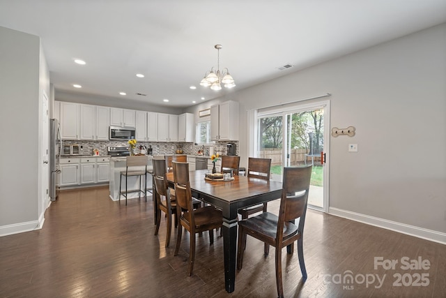 dining area featuring baseboards, visible vents, dark wood-style flooring, and an inviting chandelier