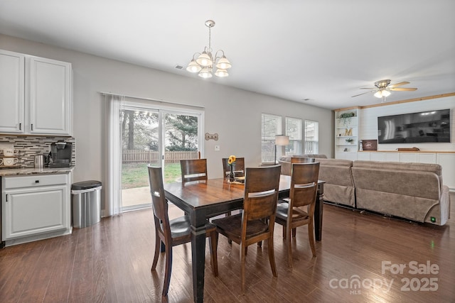 dining area featuring dark wood-style flooring, ceiling fan with notable chandelier, and plenty of natural light