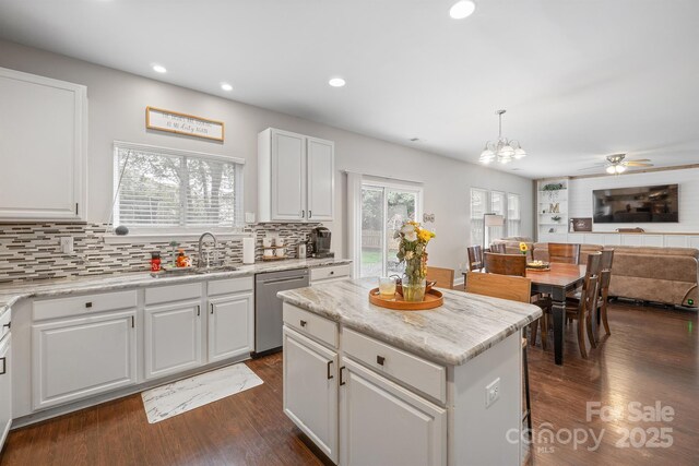 kitchen with open floor plan, dark wood-style flooring, decorative backsplash, stainless steel dishwasher, and a sink