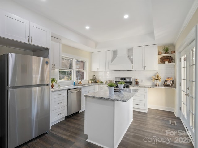 kitchen with open shelves, custom range hood, dark wood-style flooring, stainless steel appliances, and a sink