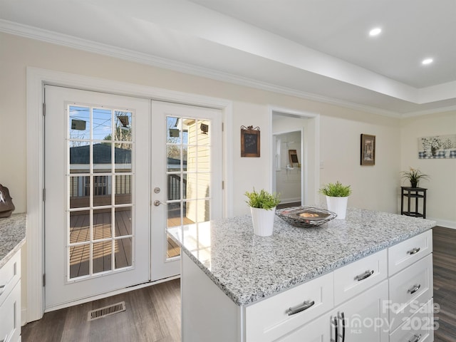kitchen with white cabinetry, visible vents, light stone counters, and dark wood finished floors