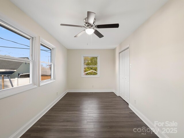 unfurnished room featuring dark wood-style floors, baseboards, and ceiling fan