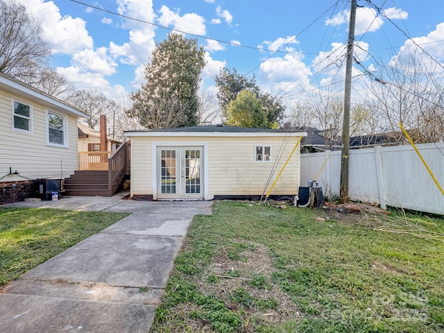 back of property featuring french doors, a wooden deck, an outbuilding, fence, and a yard