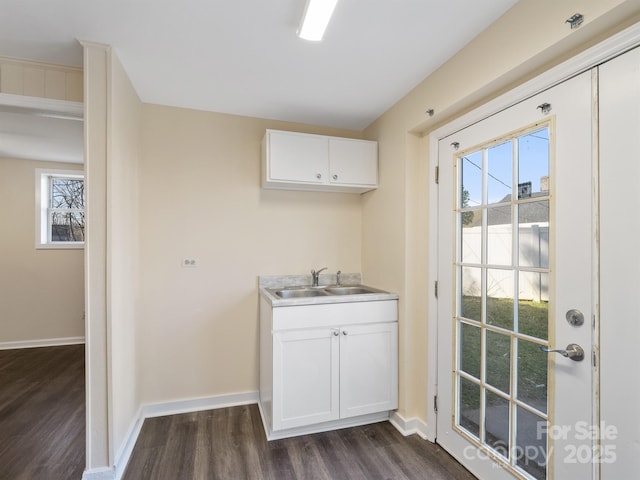 laundry room featuring a sink, dark wood-type flooring, and baseboards