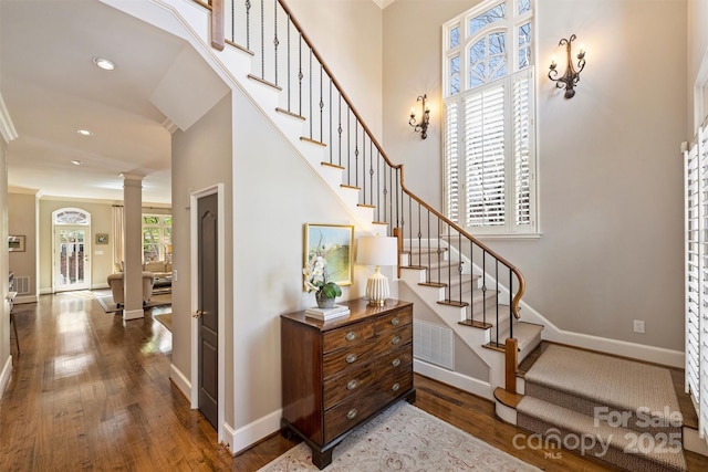 stairway with baseboards, ornate columns, wood finished floors, and recessed lighting