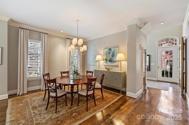 dining area with wood-type flooring, a notable chandelier, crown molding, and baseboards