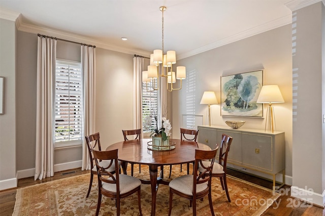 dining space featuring baseboards, crown molding, wood finished floors, and a notable chandelier