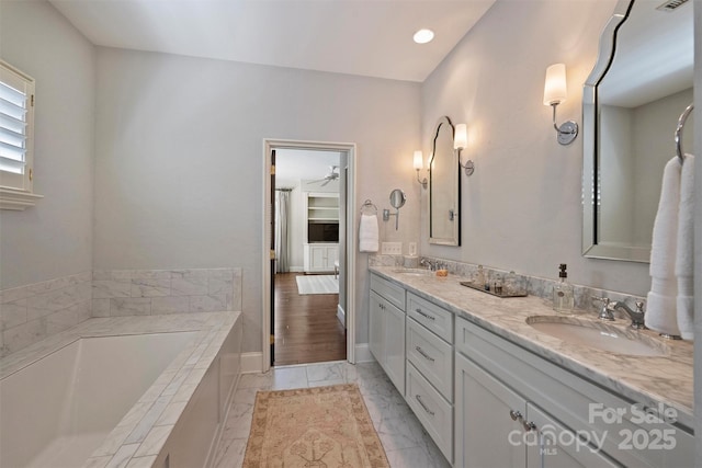 full bath with marble finish floor, double vanity, a sink, and a bath