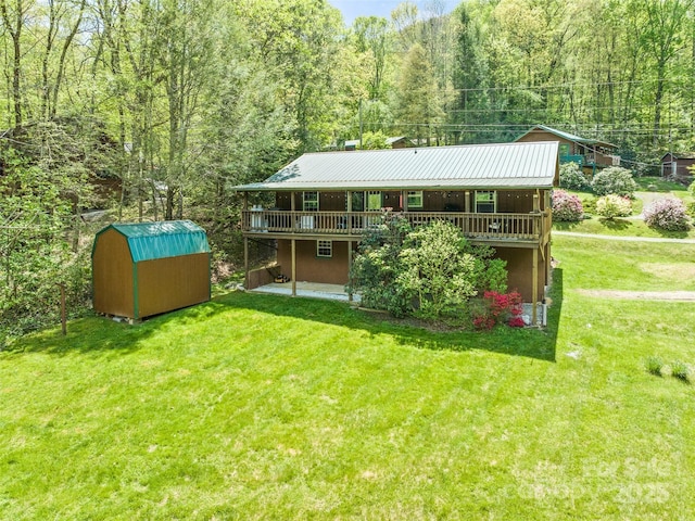 back of property with an outdoor structure, a lawn, a view of trees, and a shed