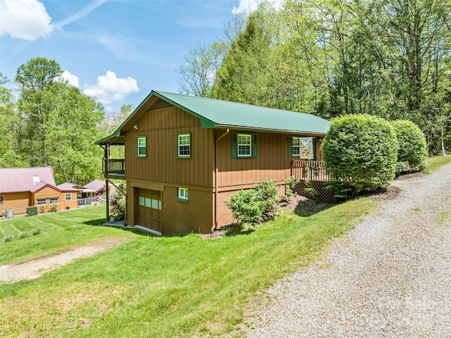 view of home's exterior with a lawn, covered porch, metal roof, an attached garage, and driveway