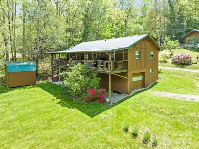 rear view of house featuring a lawn, a storage shed, a wooden deck, an outbuilding, and a garage