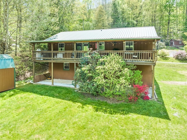back of house featuring a deck, a yard, a patio area, a storage shed, and an outbuilding