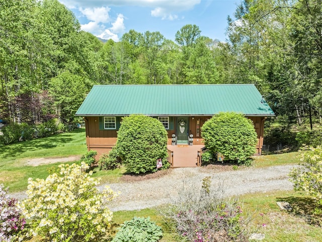 view of front facade with covered porch, board and batten siding, metal roof, and a wooded view