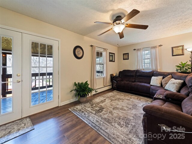 living area with baseboard heating, dark wood-style floors, a textured ceiling, french doors, and a ceiling fan