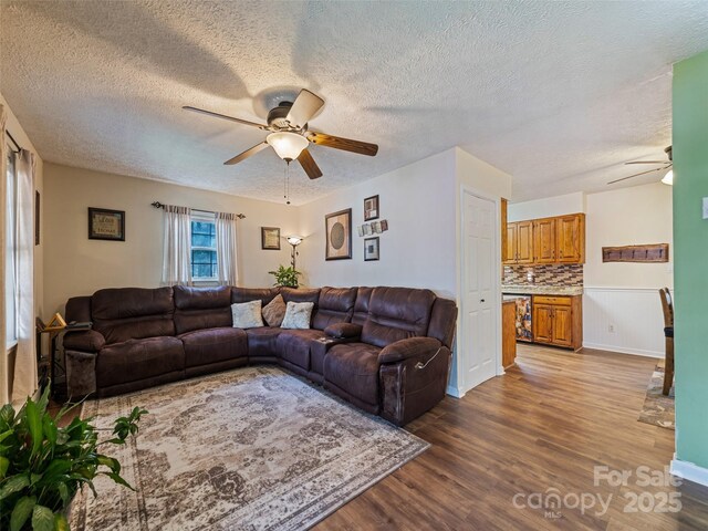 living area featuring a ceiling fan, a textured ceiling, and wood finished floors