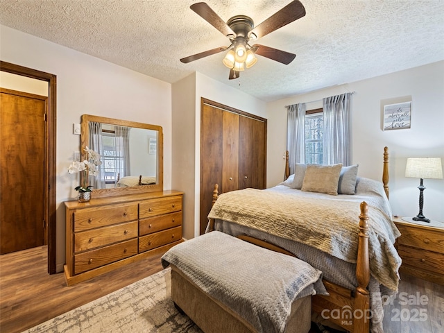 bedroom with a ceiling fan, a textured ceiling, wood finished floors, and a closet