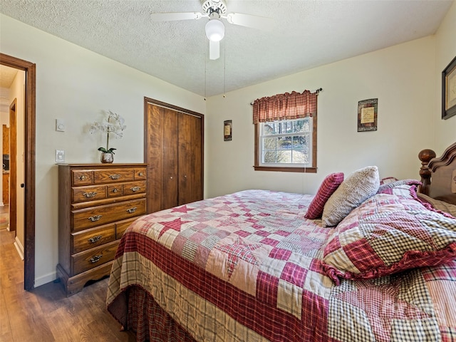 bedroom with a closet, wood finished floors, ceiling fan, a textured ceiling, and arched walkways