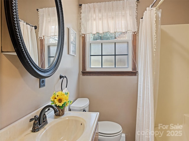 bathroom featuring a shower with shower curtain, toilet, and a sink