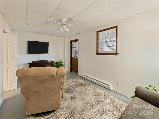 living room with finished concrete floors, a ceiling fan, a paneled ceiling, and baseboard heating