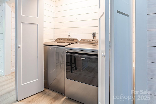 washroom with separate washer and dryer, light wood-type flooring, and laundry area
