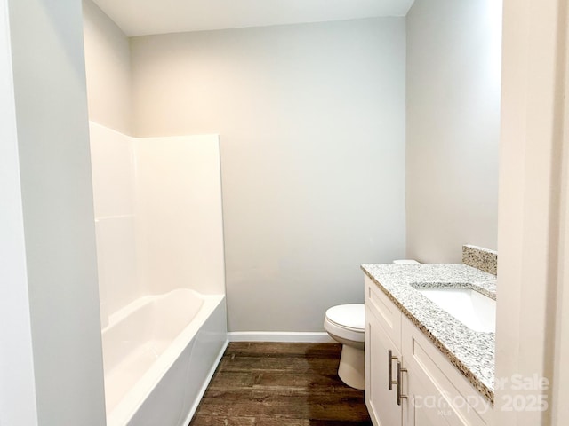 bathroom featuring toilet, vanity, baseboards, and wood finished floors
