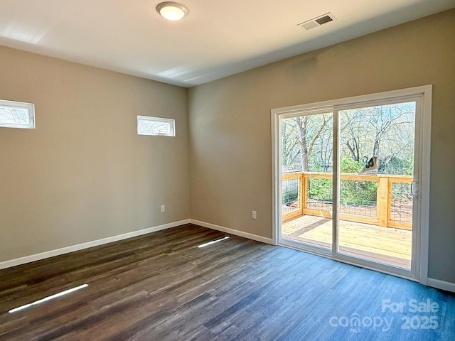 spare room with dark wood finished floors, baseboards, and visible vents