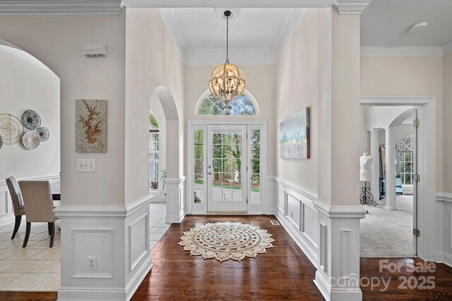 entrance foyer featuring a chandelier, a decorative wall, arched walkways, and decorative columns