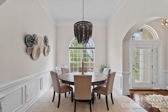 dining room featuring a chandelier, arched walkways, a wealth of natural light, and crown molding