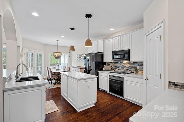 kitchen featuring a sink, a center island, black appliances, backsplash, and white cabinets