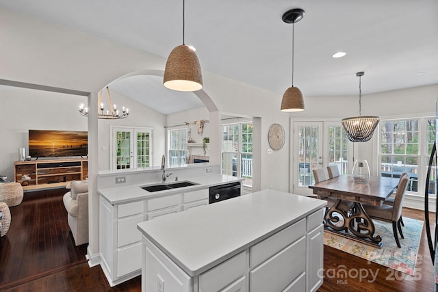 kitchen featuring black dishwasher, light countertops, a sink, a center island, and open floor plan