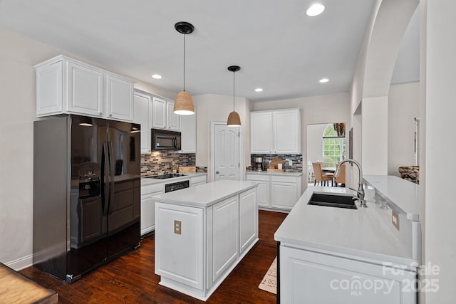 kitchen with black appliances, decorative backsplash, a kitchen island, and a sink