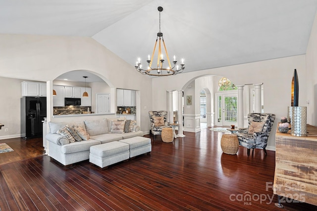 living room featuring a notable chandelier, arched walkways, dark wood-style flooring, and high vaulted ceiling